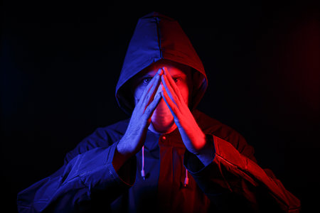 A man in a protective rubber suit and a white medical mask. Virus protection. Illuminated in red and...
