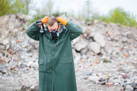 A man takes off a protective mask and he is dressed in protective clothing explores a dangerous radioactive zone.の写真素材