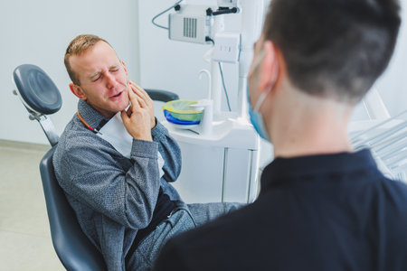 A young dentist doctor tells a male patient about dental care. A man was sitting in a dental chair at a doctor's appointment. Modern dental treatmentの写真素材
