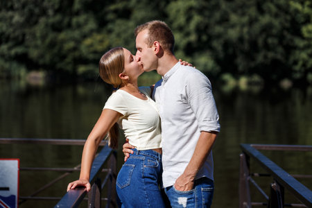 A beautiful loving young couple is standing on the banks of the river. Happy married couple on vacation by the lakeの写真素材