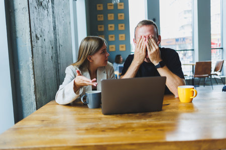 Young colleagues managers are sitting at the table and laughing. Concept of business cooperation and teamwork. Young smiling people at the table in the office with a laptop. Modern successful peopleの写真素材