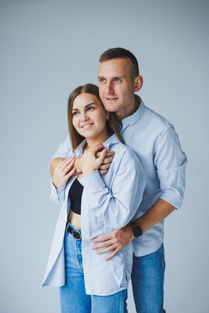Photo of happy couple wearing white shirts, blue jeans, isolated white background. A man and a woman are hugging on a white backgroundの写真素材
