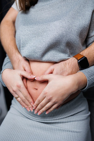 Happy married couple. Pregnant woman and loving man hugging her belly on white background. Sensation of movement of the baby as a couple on the belly of the pregnant woman.の写真素材