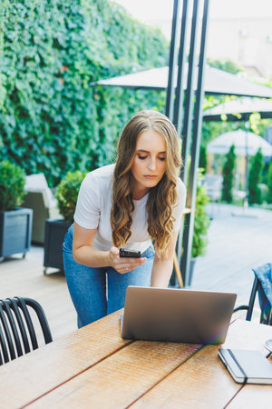 Young woman sitting on the terrace of a cafe on the street of a modern cafe. Woman sitting at table...