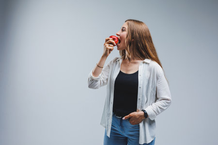 Cute brunette woman in white shirt holding red apple in hand standing on isolated white background...