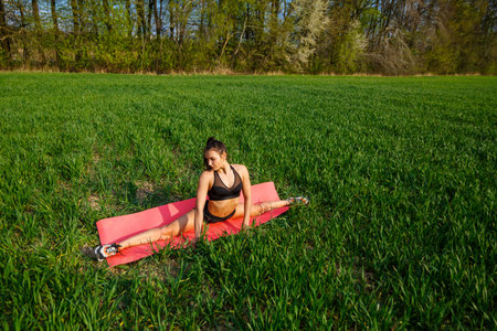 Young athletic woman doing longitudinal splits outdoors. Girl go in for sports, healthy lifestyle,...