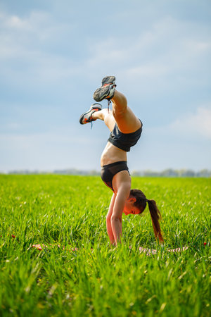 Girl acrobat performs a handstand. The model stands on her hands, doing gymnastic splits against the...
