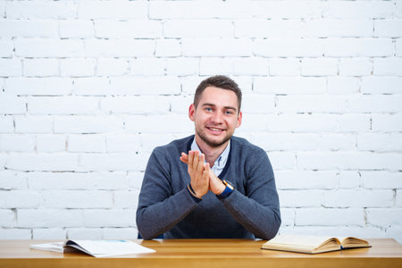 A young businessman guy sits at a table with a book