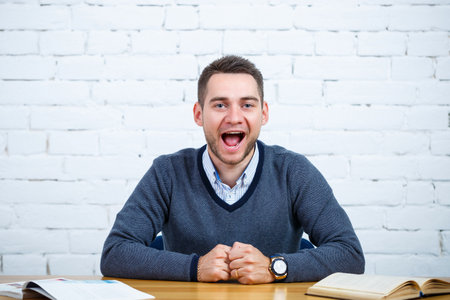 A young businessman guy sits at a table with a bookの写真素材