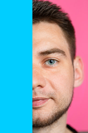 A man is smiling and holding an empty cardboard blue banner over an isolated pink background. Happy face thinking about a question. Place for an inscription. Idea for recording good thoughts.の写真素材
