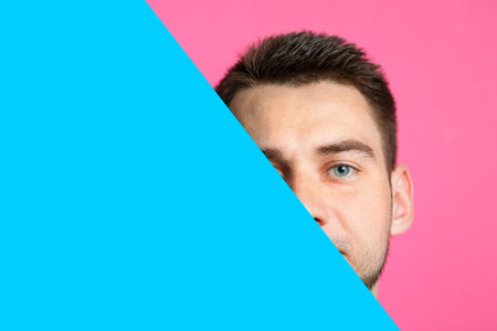 A man is smiling and holding an empty cardboard blue banner over an isolated pink background. Happy...