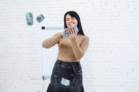 Photo of a charming woman with a smile holding money in her hands and throwing it into the airの写真素材