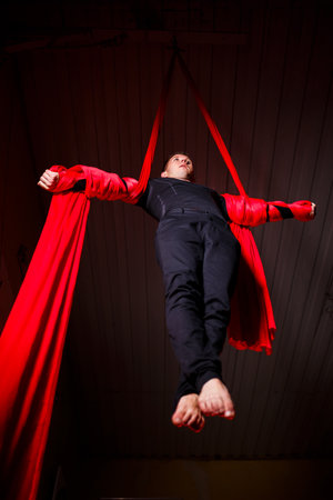 Silhouette male aerial gymnast perform on red canvasesの写真素材