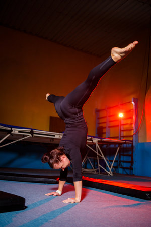 Young sportive girl doing handstand exercise. Young woman doing twine while standing on hands