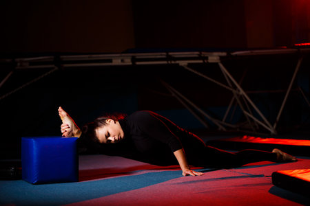 Young woman practices twine sitting. Athletic girl doing gymnastics in the gym. Active lifestyleの写真素材
