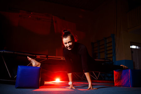 Young woman practices twine sitting. Athletic girl doing gymnastics in the gym. Active lifestyleの写真素材
