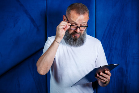 Adult male mentor, director, businessman in glasses and a suit studying documents while sitting at the table. Working day conceptの写真素材