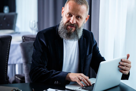 An adult male businessman is working on a new project and looking at the stock growth charts. Sits...