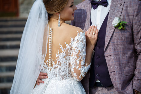 The bride in a white wedding dress and groom in a suit on the background of a brick building with large stepsの写真素材