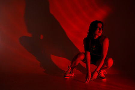 Photoshoot of a young brunette in a photo studio. Beautiful slender woman in a black top and shorts...