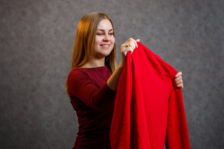 beautiful girl tries on a red sweaterの写真素材