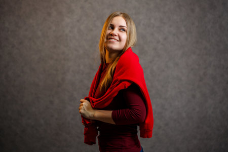Girl tries on a red sweater on a gray backgroundの写真素材
