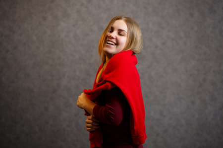 Girl tries on a red sweater on a gray backgroundの写真素材