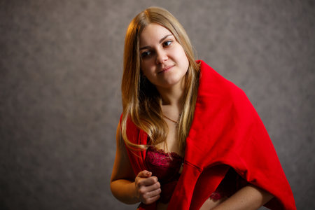 Girl tries on a red sweater on a gray backgroundの写真素材