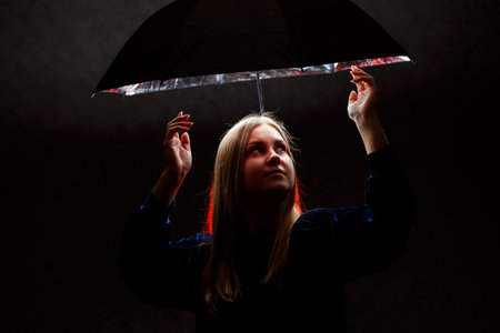 girl stands under an umbrella against a dark backgroundの写真素材
