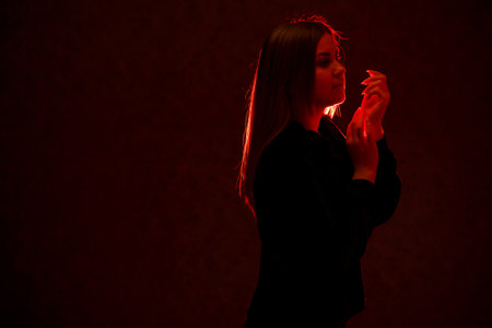 Girl with blond hair emotionally posing on a gray background. Her hair is lit in red