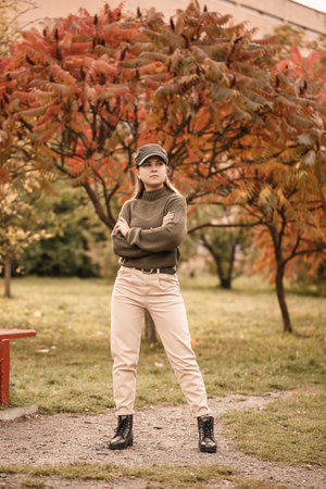 Young beautiful girl dressed in stylish clothes, green sweater and beige pants, in an autumn park with beautiful treesの写真素材