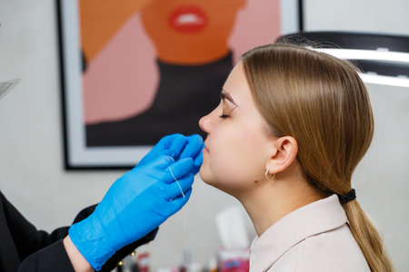 A woman permanent makeup artist draws a sketch of the eyebrows on the face of her client.の写真素材