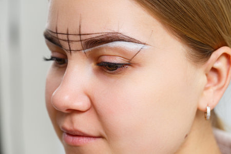 Makeup artist applies eyebrow tint for the permanent makeup of a young girl. Professional make-up and cosmetic face careの写真素材