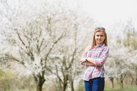 Beautiful girl in flowering trees in early spring. Bright sun and natureの写真素材