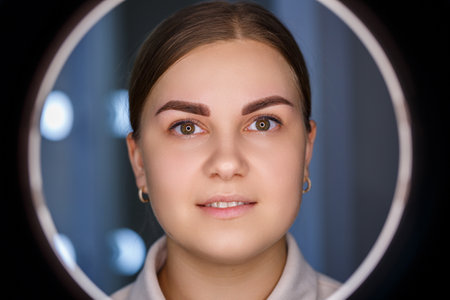 A close-up of the face of a young woman who has just had a permanent eyebrow tattoo done.の写真素材