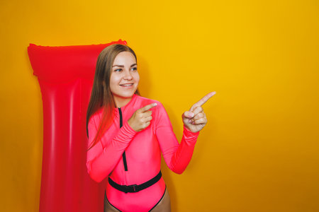 Young woman slim body pink one piece swimsuit on pink air mattress isolated on bright yellow color...