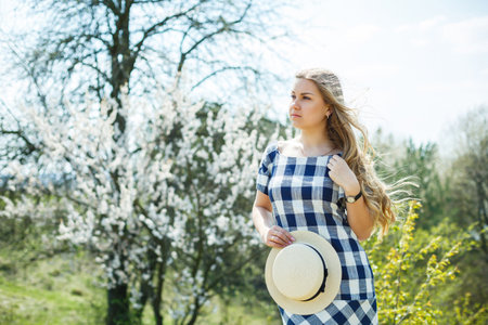 beautiful girl in a dress walking in the spring forest where the trees bloomの写真素材