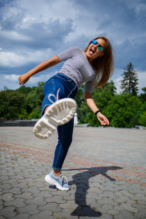 A beautiful girl with blond long hair of European appearance. Dressed in jeans and a T-shirt. Walk...
