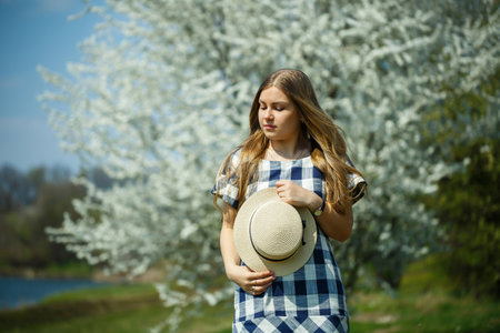 beautiful girl in a dress walking in the spring forest where the trees bloomの写真素材
