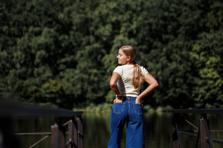 A beautiful girl of European appearance. A young woman is walking by the river. Dressed in jeans and a T-shirt.の写真素材