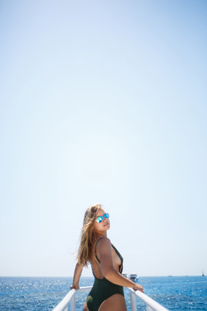 A girl with a beautiful figure in a green swimwear. She is on a white yacht in the red seaの写真素材