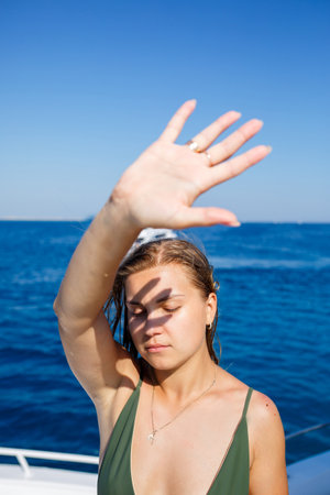 Girl in a swimsuit on a background of the sea. The bright sun shines on the face. There is a shadow...