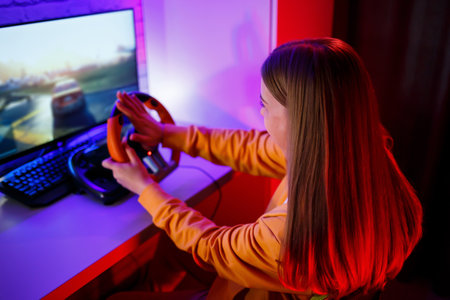 girl gamer playing racing on a computer. She uses a steering wheel. emotional play