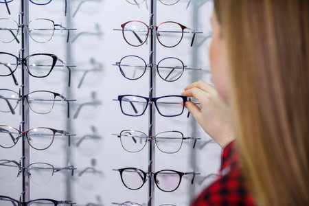 The girl in the shirt takes out and measures on herself glasses