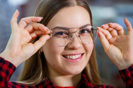 The girl in the shirt takes out and measures on herself glasses