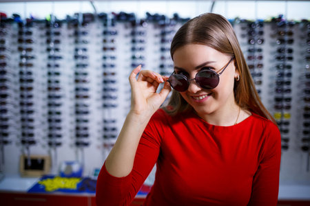 Beautiful young girl chooses sunglasses in an optics store.の写真素材