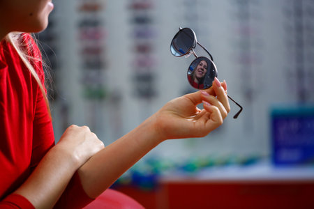 Beautiful young girl chooses sunglasses in an optics store.の写真素材