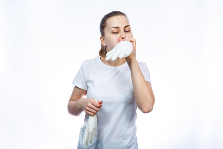 The girl holds white medical gloves in her hands. Protection against germs and the virus. She is in a white T-shirt on a white background.の写真素材