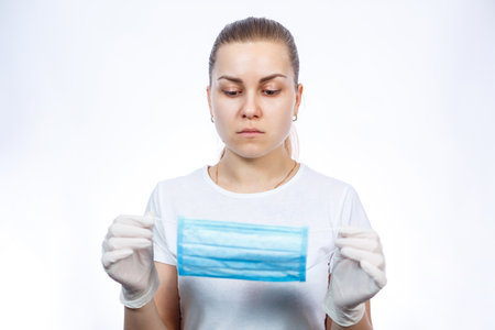 woman health worker demonstrates how to wear a protective medical surgical mask against the virus....