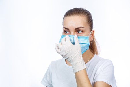 woman health worker demonstrates how to wear a protective medical surgical mask against the virus....